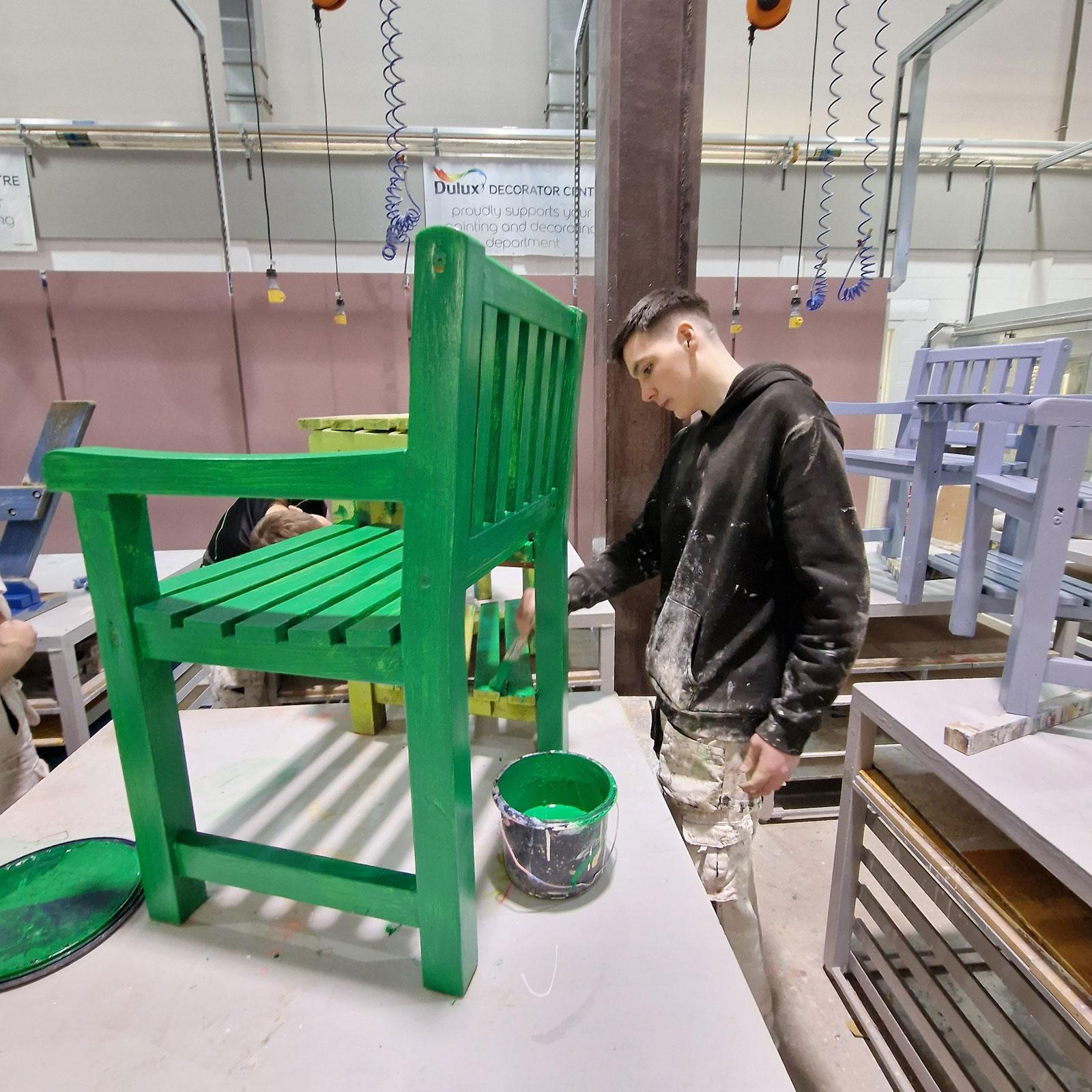 Picture of a student painting garden furniture.